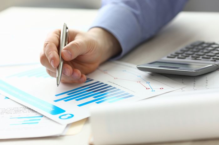 Foto: Person zeigt mit Stift auf Akten